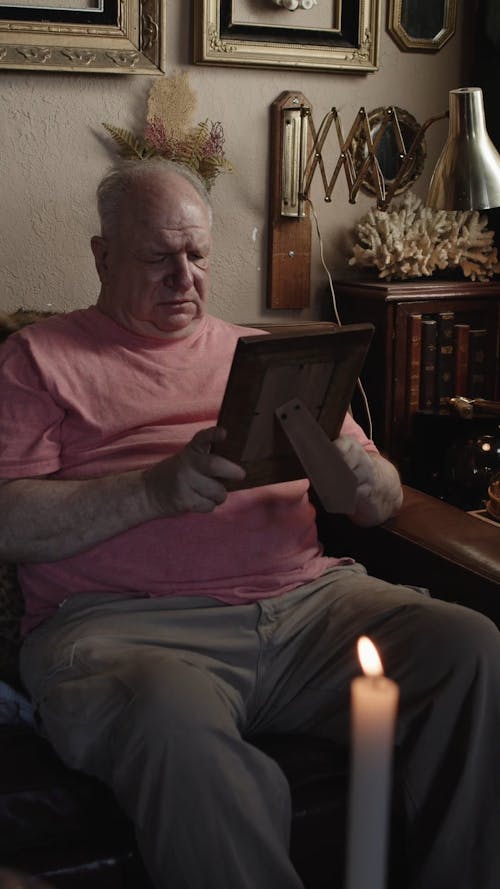 An Elderly Man Looking at a Picture Frame