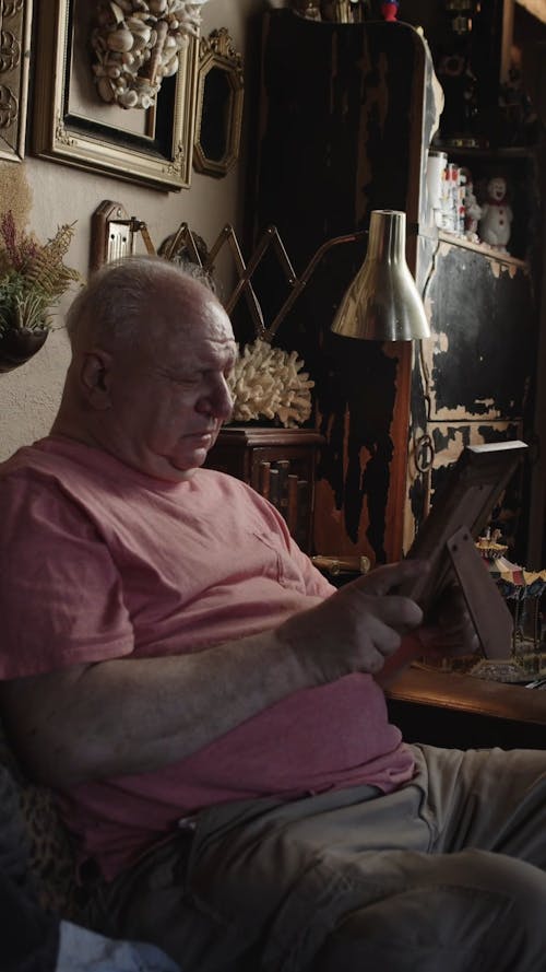 An Elderly Man Looking at a Picture Frame