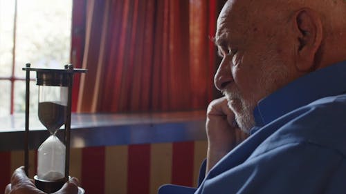 An Elderly Man Looking at an Hourglass