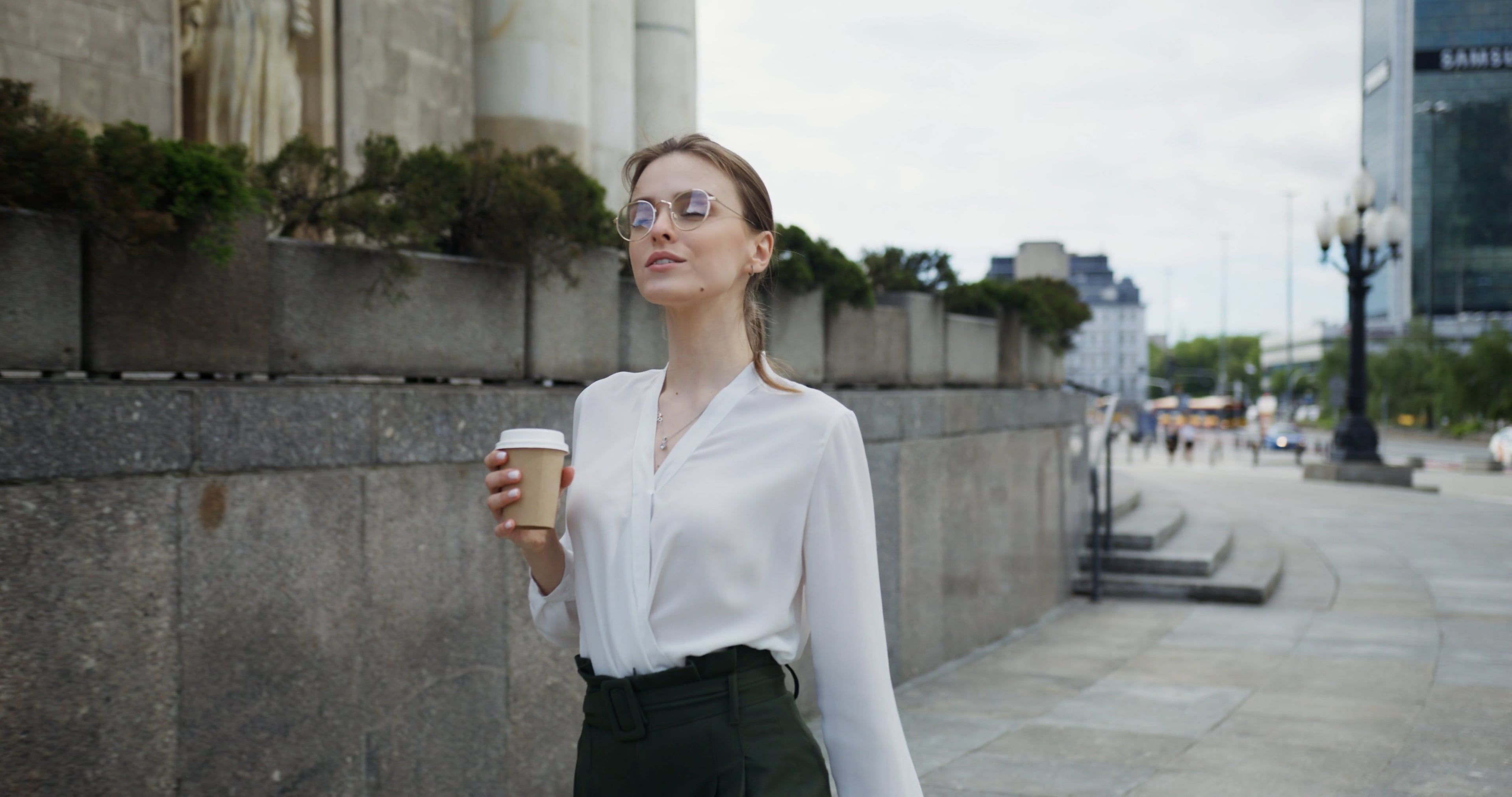 A Woman Holding a Cup of Coffee while Walking Free Stock Video Footage ...