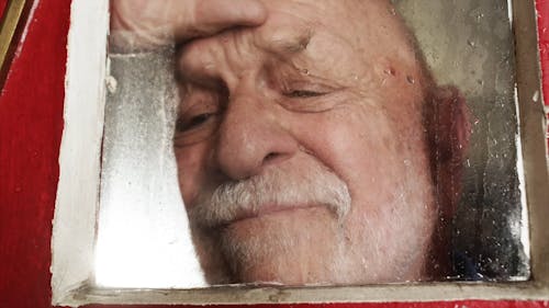 An Elderly Man Looking through a Glass Window