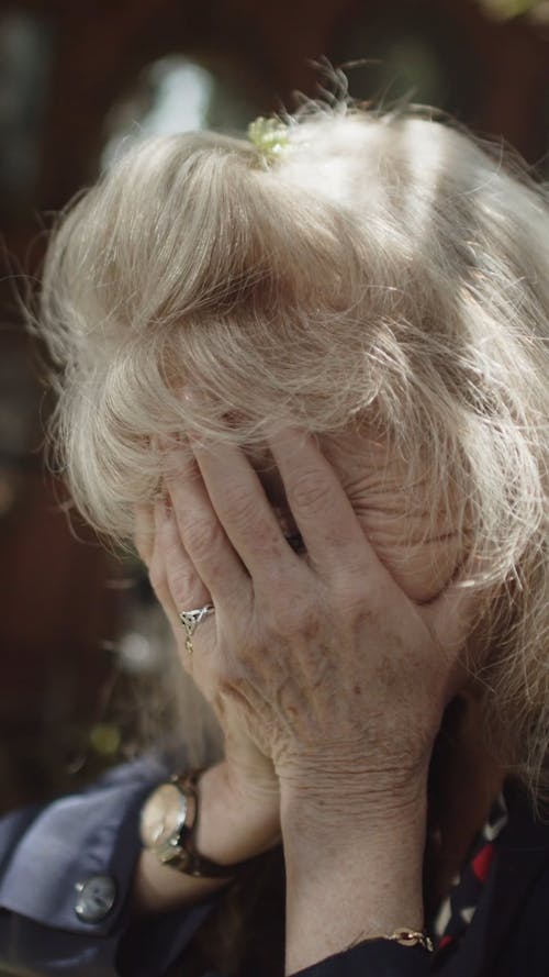 An Elderly Woman Covering Her Face with Her Hands