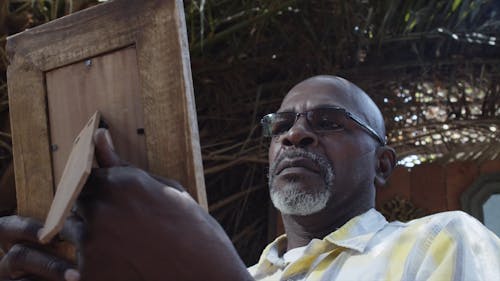 A Man with Sad Eyes Staring at a Picture Frame