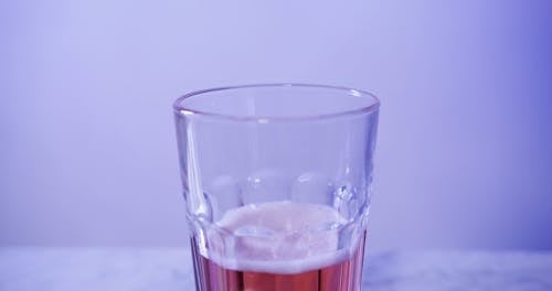 A Person Pouring a Red Beer in a Glass