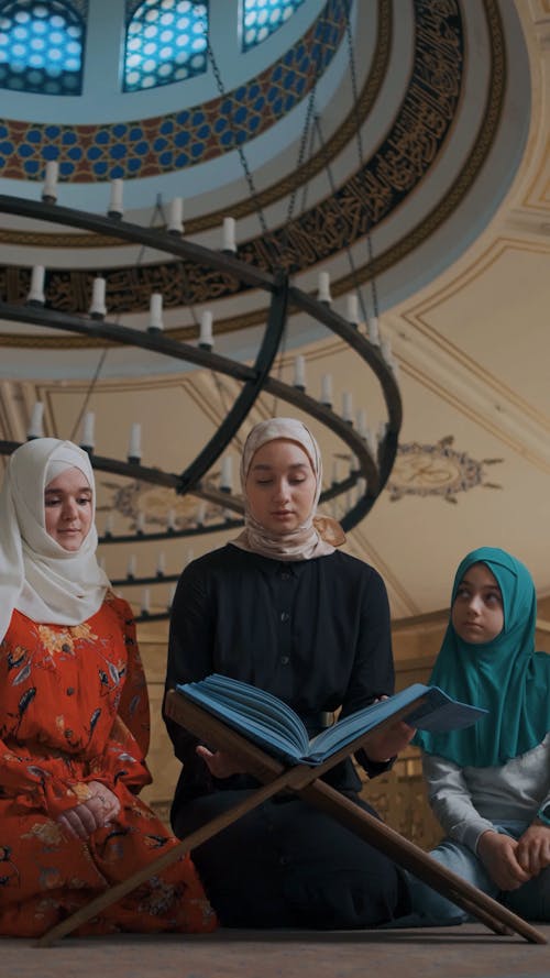 Two Women and a Girl Praying while Reading a Quran