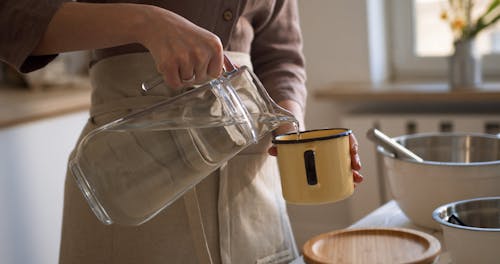 A Woman Pouring water In A Cup