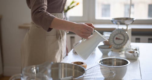 Person Pouring Milk in a Stainless Bowl