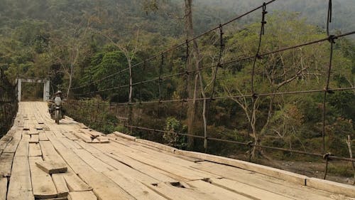 A Person Crossing a Wooden Bridge on a Motorcycle