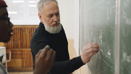 A Student and his Teacher Writing on the Board