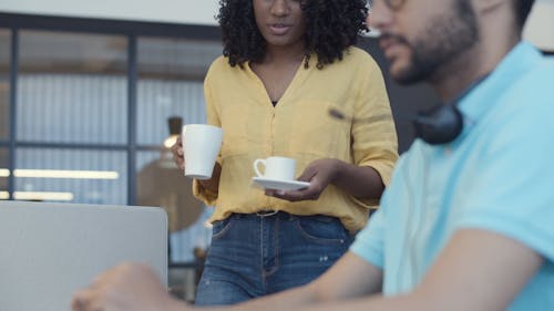 A Woman Giving a Cup of Coffee to a Coworker