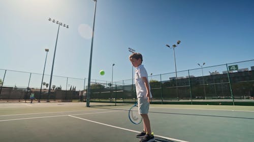 A Boy Bouncing a Tennis Ball
