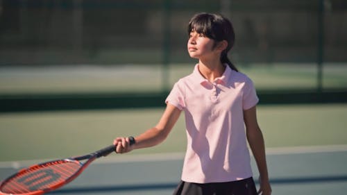 A Girl Bouncing A Tennis Ball Off Her Racket
