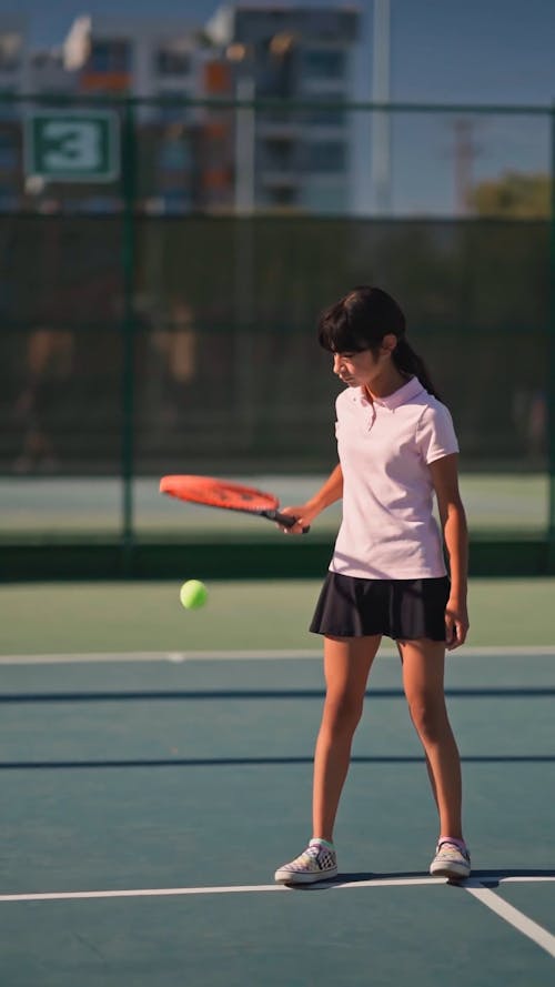 A Girl Bouncing A Tennis Ball With Her Racket