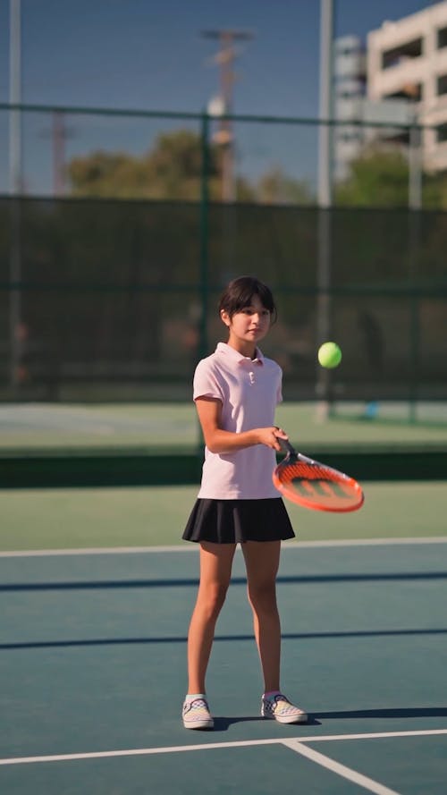 A Girl Bouncing A Tennis Ball Off Her Racket