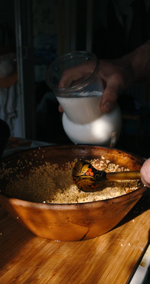 A Person Pouring Milk on a Wooden Bowl