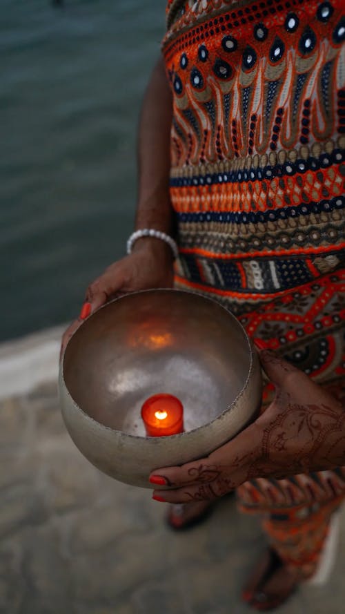 A Female Person Holding a Bowl with a Lighted Candle