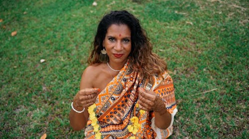 A Woman in a Sari Putting on a Necklace of Flowers