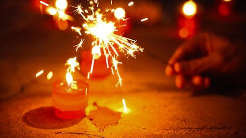 A Close up of a Person Holding Sparklers next to Candles
