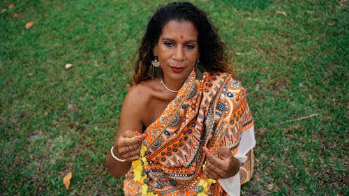 A Woman Putting on a Necklace of Flowers