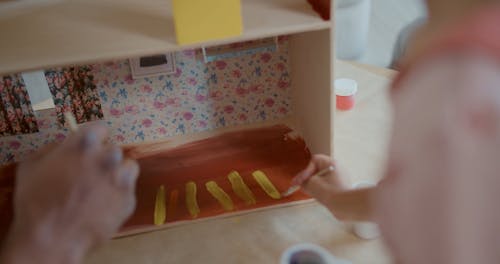 Father and Daughter Painting a Dollhouse Together