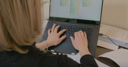 Back View of a Person Typing on Laptop