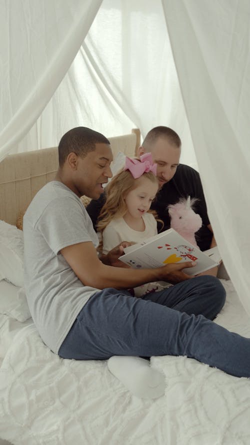 People Sitting on Bed While Reading a Book