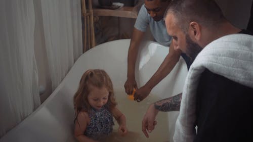 A Girl Playing Rubber Ducks While Soaking on a Bath Tub