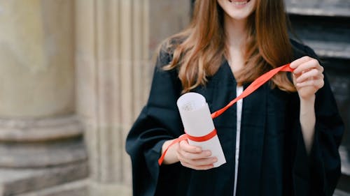 A Woman Removing the Ribbon and Unfolding Her College Diploma