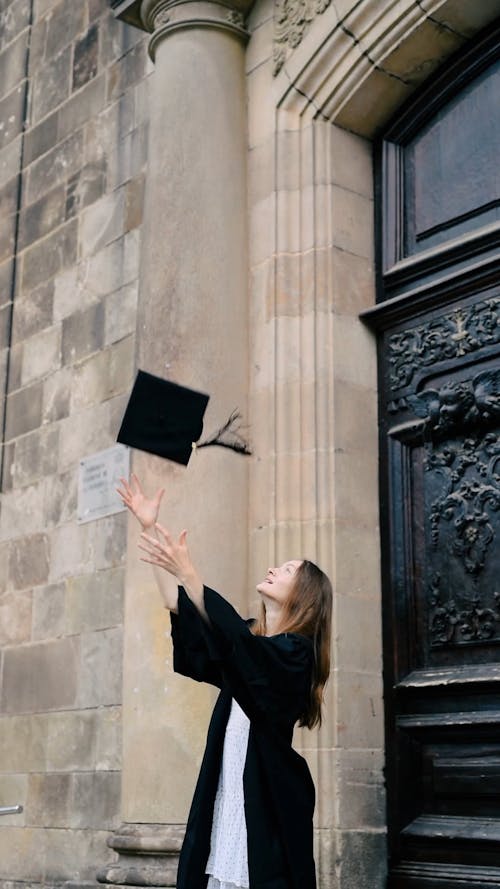 A Woman Throwing Her Graduation Cap and Spinning in Happiness
