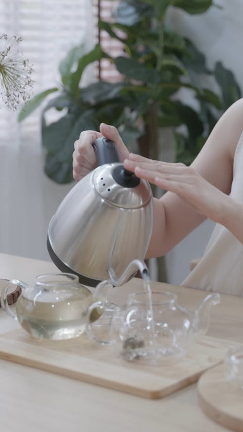 A Woman Pouring Hot Water on the Teapot