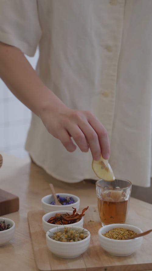 Person Putting a Slice of Lemon in Tea