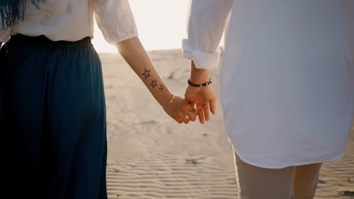 Back View of a Couple Walking While Holding Hands in the Dessert