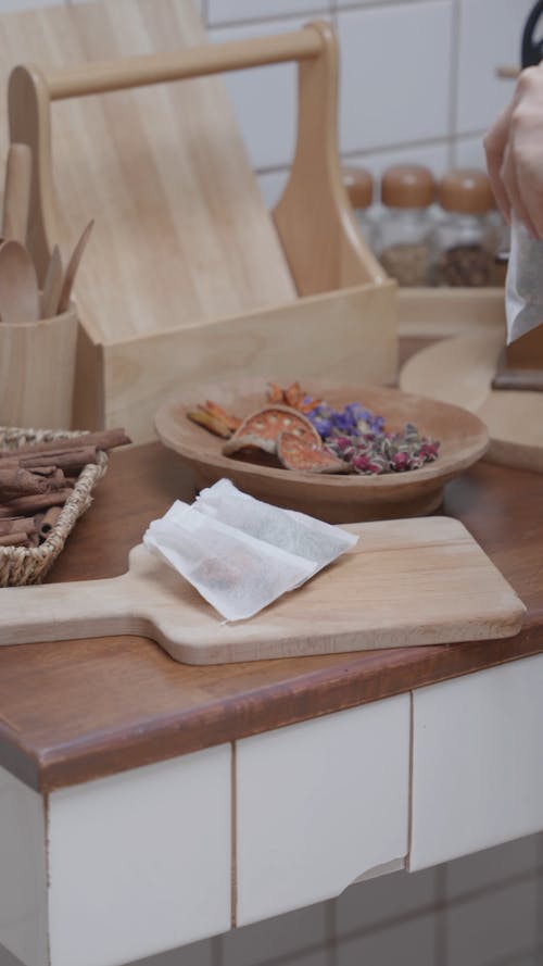 A Person Putting a Piece of Tea Bag on a Wooden Chopping Board