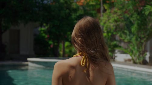 A Young Woman in a Bikini Sitting by the Poolside