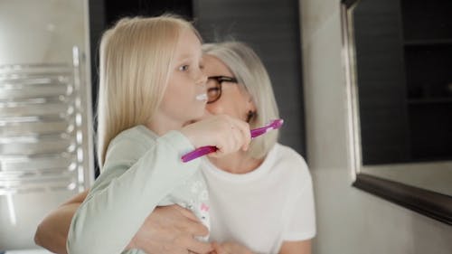 Grandmother Helping Granddaughter Brushing Teeth