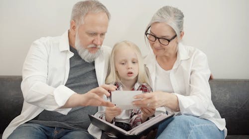 Elderly Couple Looking at a Photo Album with Granddaughter