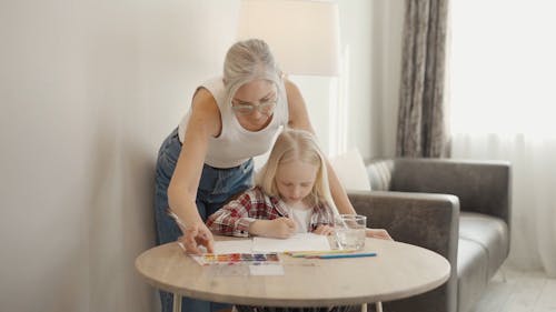 An Elderly Woman Painting on Paper with Her Granddaughter