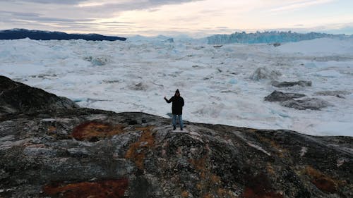 A Man Having His Photo Taken with an Iceberg Background