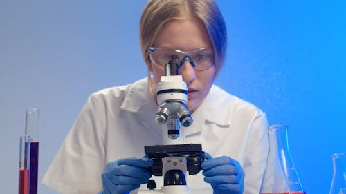 A Woman Observing Specimen Under A Microscope