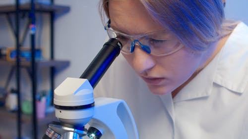 A Female Scientist Looking Into A Microscope