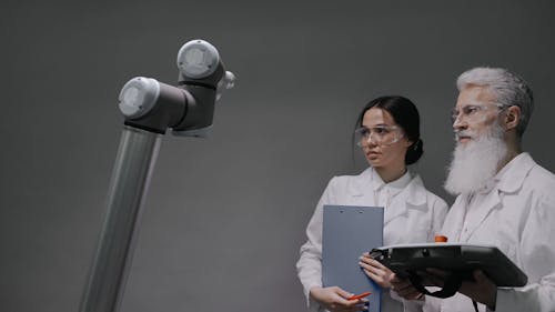 A Man and a Woman Looking at a Robotic Arm