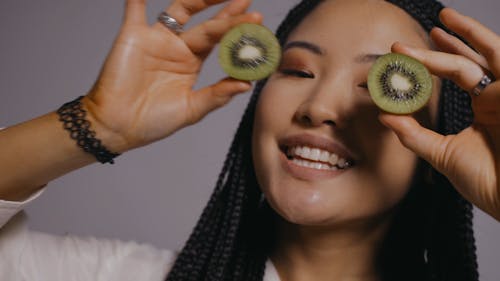 Woman Covering Her Eyes with Kiwi Slices