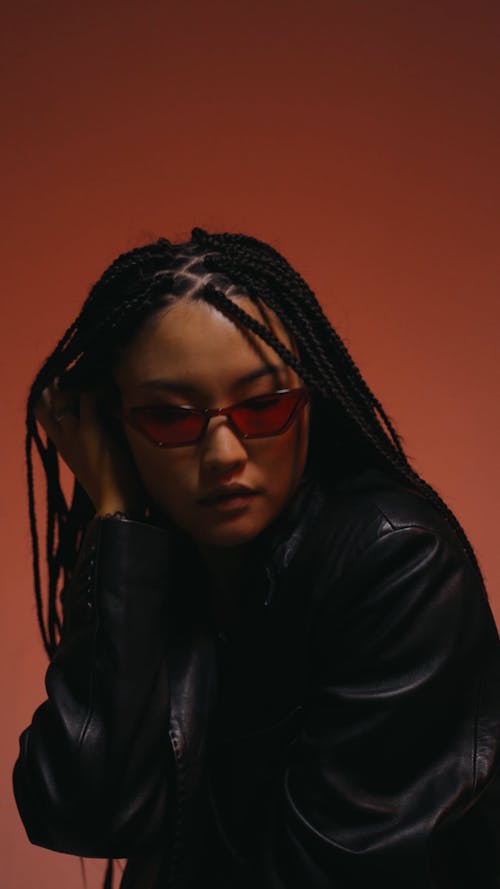 A Woman Removing Eyeglasses While Sitting and Posing 