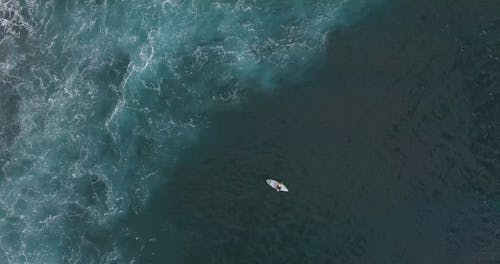 Drone Footage of a Person Sitting on Surfboard