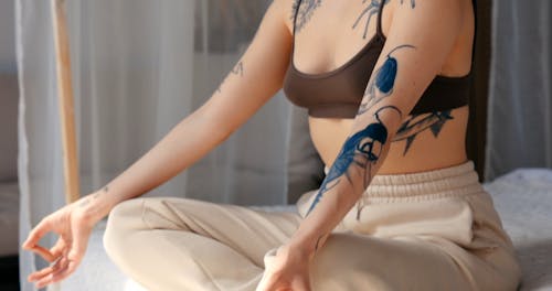 A Tattooed Woman Meditating in Bed