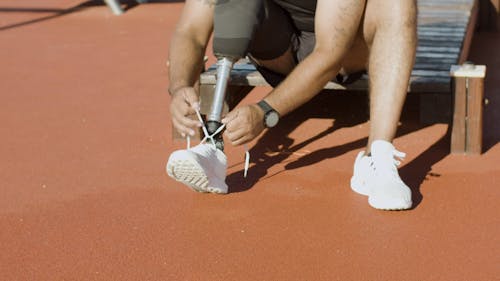 A Man with Prosthetic Leg Tying His Shoes