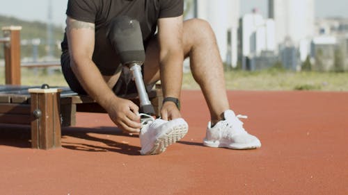 A Man with Prosthetic Leg Tying His Shoes