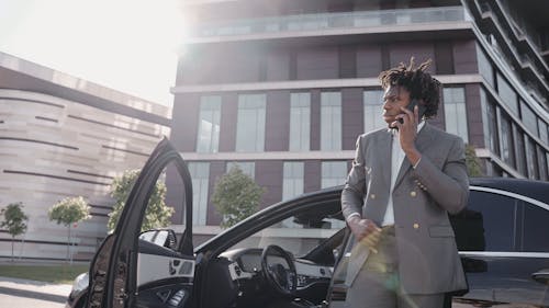 A Man Talking on the Phone while Leaning on Car
