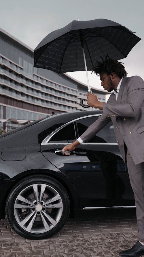 A Man in a Gray Suit Opening the Car Door for His Boss