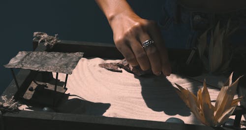 A Person Using a Rake to Make Patterns on Sand 